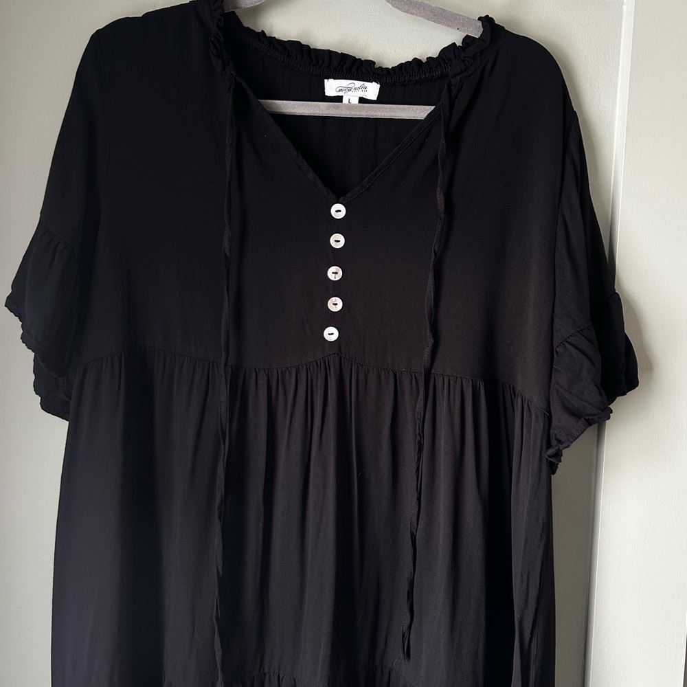 black tiered smock dress with ruffle sleeves and a tie-neck detail.